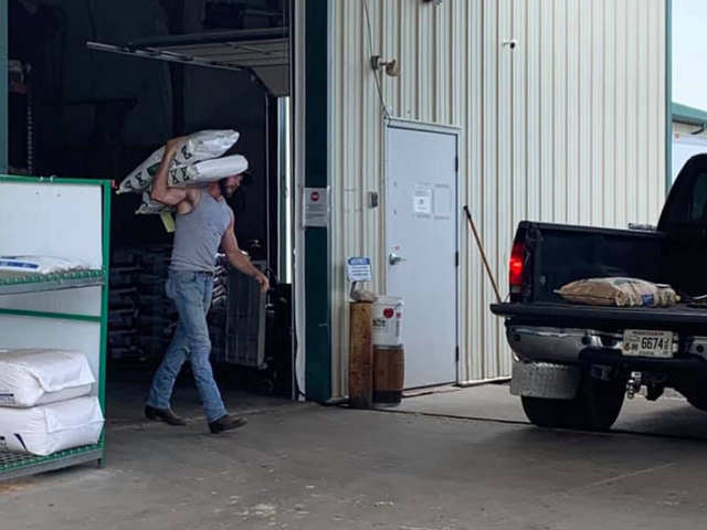 Person Loading bags into the bed of a pickup truck at Feed Bucket, Simpsonville, KY